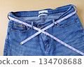 Blue jeans with measuring tape on color background. 134708688