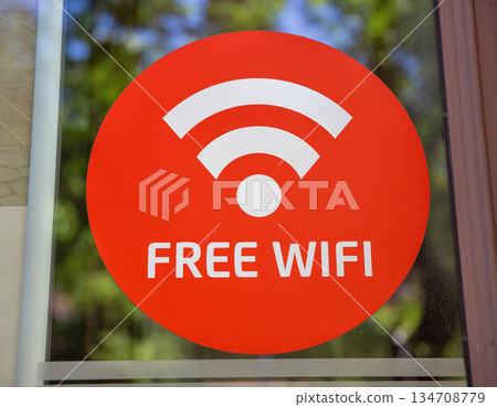 Free wifi sign sticker on glass window closeup. Free wifi sign sticker on glass window closeup. 134708779