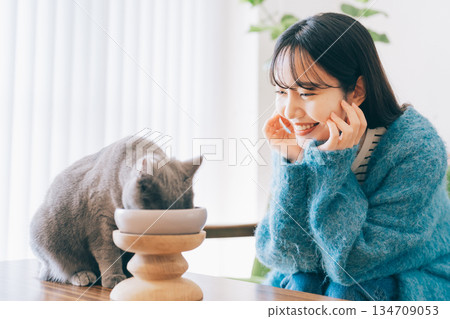 Woman watching over cat eating food Woman watching over cat eating food 134709053