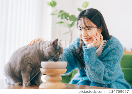 Woman watching over cat eating food 134709057