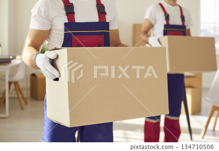 Close up of man mover worker holding a cardboard box in hands standing in new apartment. 134710506