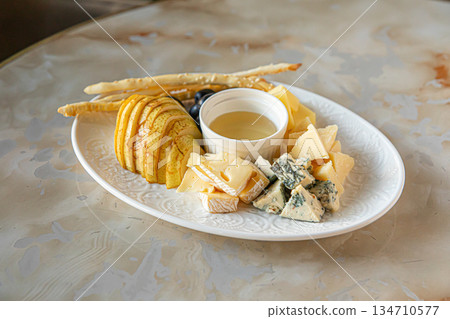 Cheese platter with honey pear and crackers Cheese platter with honey pear and crackers 134710577