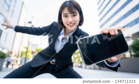 微笑的女商人正在戶外辦公室區分發智慧型手機,用於IT服務廣告橫幅宣傳。 微笑的女商人正在戶外辦公室區分發智慧型手機,用於IT服務廣告橫幅宣傳。 134711315