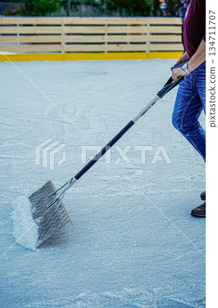 Vertical Shot of Man Cleaning Snow from Ice with Shovel 134711707