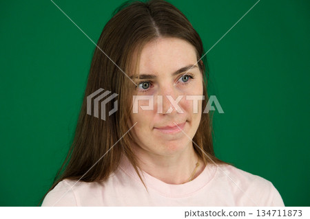 portrait of young woman appears thoughtful as she holds her cellphone, reflecting on something important on light background 134711873