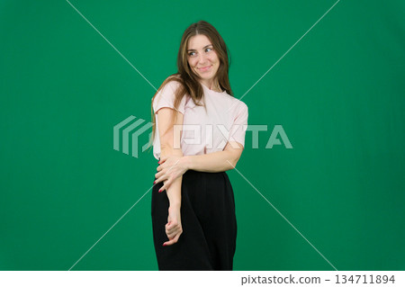 Young hispanic woman poses with hand on cheek for sleep gesture against an isolated orange wall in studio sleepiness. 134711894