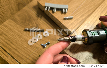 Small parts for furniture assembly against a background of wooden panels. Assembling furniture at home and doing home repairs yourself. High quality photo Small parts for furniture assembly against a background of wooden panels. Assembling furniture at home and doing home repairs yourself. High quality photo 134712428