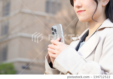 A woman using a smartphone in an office district A woman using a smartphone in an office district 134712522
