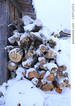 Firewood logs outside under the snow. Preparing firewood for winter heating in a Russian village, an environmentally friendly fuel. Environmental protection concept, 134712552