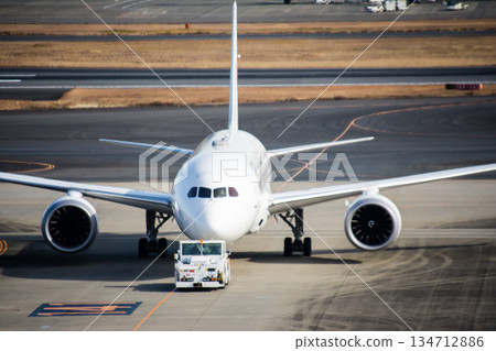 陽光明媚，一架巨大的純白色飛機停在東京羽田機場。 134712886