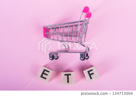 ETF - Exchange Traded Fund, word on wooden cubes, on a pink background with a shopping trolley. ETF - Exchange Traded Fund, word on wooden cubes, on a pink background with a shopping trolley. 134713004