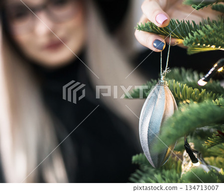 Closeup image of woman decorating Christmas tree with baubles Closeup image of woman decorating Christmas tree with baubles 134713007