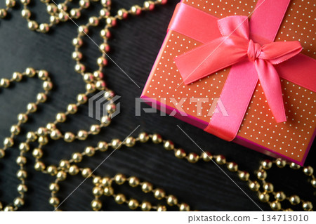 Gift box with gold garland on wooden background Gift box with gold garland on wooden background 134713010