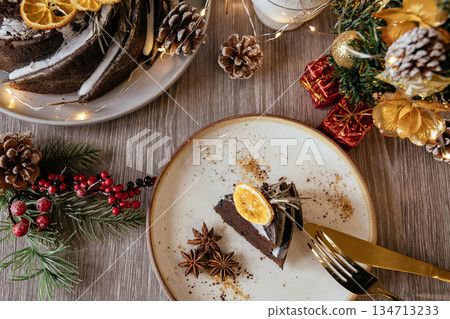 A slice of fruit pound cake, tea mug, Christmas tree branch on white wooden background, closeup view 134713233