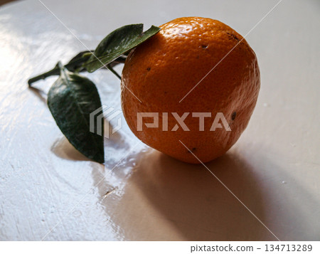 Tangerine with leaves in the background light on a white board 134713289