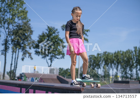 The girl gathers thoughts, concentrates before doing a dangerous skateboard trick on the ramp of the skatepark The girl gathers thoughts, concentrates before doing a dangerous skateboard trick on the ramp of the skatepark 134713557