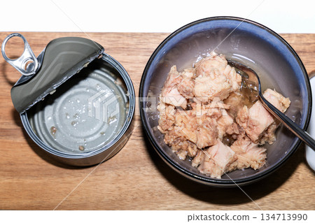 Opened empty tuna can with tuna in bowl. 134713990