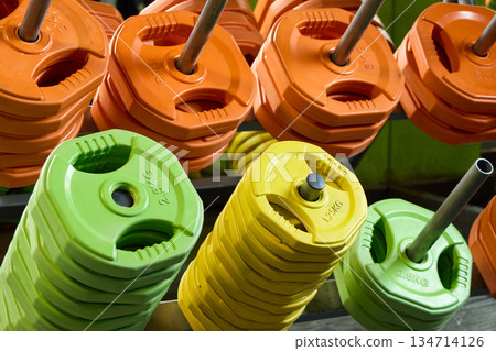 A vibrant array of weight plates stacked on a rack, ideal for strength and fitness workouts. 134714126