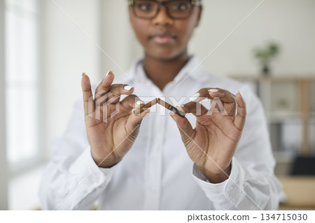 Young African American woman quits unhealthy habit and breaks cigarette in her hands 134715030
