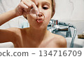 Child blowing soap bubbles during bath time at home 134716709