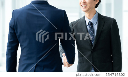 two male businessmen shaking hands 134716802