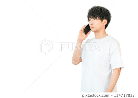 一位年輕的亞裔男子正在用他的智慧型手機打電話 一位年輕的亞裔男子正在用他的智慧型手機打電話 134717832