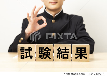 一名男學生用寫著「考試成績」的方塊比出「OK」手勢 一名男學生用寫著「考試成績」的方塊比出「OK」手勢 134718515