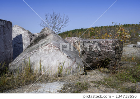 Pyramidal and cubic stone figures in an abandoned marble quarry in the autumn forest 134718656