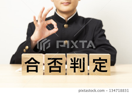 A male student making an OK sign with a block that says "Pass/Fail Decision" A male student making an OK sign with a block that says "Pass/Fail Decision" 134718831