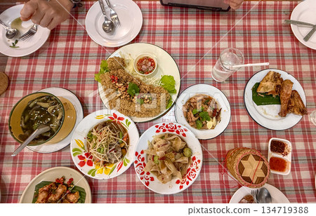 Topview of Isan food table with som tam, nam tok pork, grilled chicken, sticky rice basket. Local northeast Thai dishes arranged for casual eating. Topview of Isan food table with som tam, nam tok pork, grilled chicken, sticky rice basket. Local northeast Thai dishes arranged for casual eating. 134719388