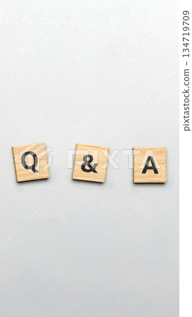 Top shot of wooden cubes spelling out the common abbreviation of Q And A, meaning questions and answers, centered on a white textured background. Concept of Questions and Answers 134719709