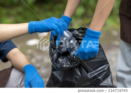 Volunteers wearing aprons and gloves in a cleanup activity. Holding trash bags filled with garbage. Protecting the environment by cleaning up litter 134719745
