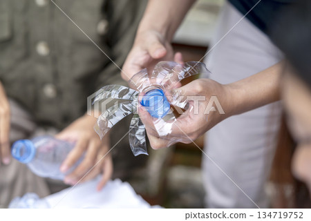 People gathered outdoors, actively participating in a recycling initiative. Decorating with plastic bottles promotes environmental sustainability. Spirit of eco-consciousness 134719752