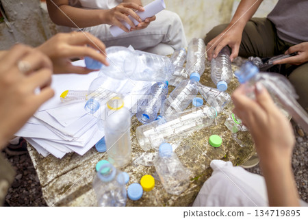 People gathered outdoors, actively participating in a recycling initiative. Decorating with plastic bottles promotes environmental sustainability. Spirit of eco-consciousness People gathered outdoors, actively participating in a recycling initiative. Decorating with plastic bottles promotes environmental sustainability. Spirit of eco-consciousness 134719895
