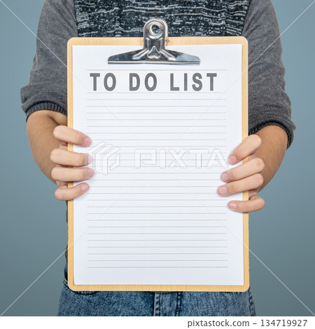 Person holding a clipboard with a 'To Do List' printed on it. The clipboard is blank and ready for tasks or notes, perfect for illustrating productivity and organization. Mockup or Copy space Person holding a clipboard with a 'To Do List' printed on it. The clipboard is blank and ready for tasks or notes, perfect for illustrating productivity and organization. Mockup or Copy space 134719927