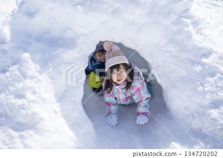 Children playing in snow igloos in a snowy park Children playing in snow igloos in a snowy park 134720202