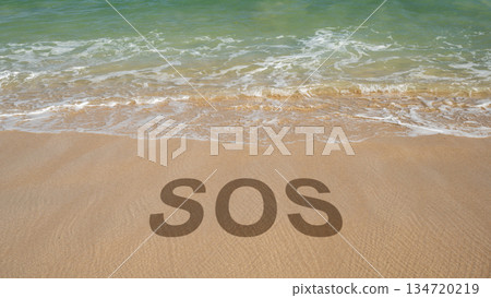 SOS message written in the sand on a beach with waves coming in. Concept for emergency, help, or danger. Vacation on the beach with SOS word. 134720219