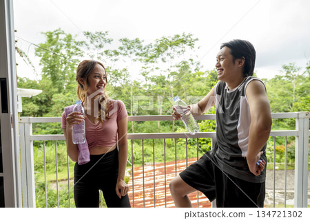Indonesian southeast asian people wearing sportswear and a towel around neck is holding a water bottle after a workout. They appear refreshed and healthy Indonesian southeast asian people wearing sportswear and a towel around neck is holding a water bottle after a workout. They appear refreshed and healthy 134721302