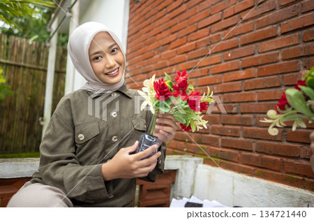 Indonesian southeast asian woman gathered outdoors, actively participating in a recycling initiative. Decorating with plastic bottles promotes environmental sustainability. Spirit of eco-consciousness 134721440