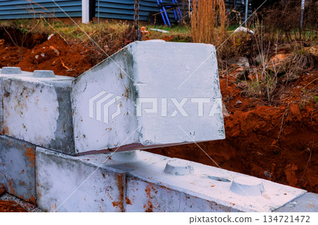 Workers place concrete blocks on construction site near building for retaining walls Workers place concrete blocks on construction site near building for retaining walls 134721472