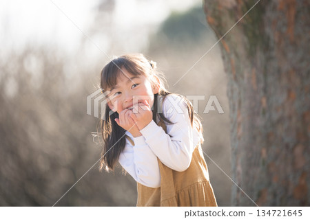 A girl peeking out from behind a tree, playing traditional games like hide-and-seek and Daruma-san koronda in the park 134721645