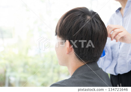 A faceless back view of a man getting his hair cut or styled 134721646
