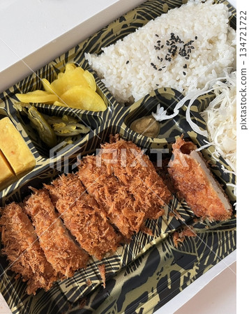 Crispy tonkatsu, a Japanese-style breaded and deep-fried pork cutlet, served with shredded cabbage and drizzled with savory sauce. A delightful balance of crunchy texture and juicy meat. 134721722