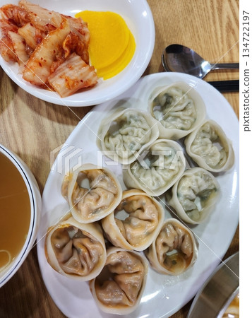 Steamed or fried mandu dumplings served alongside fermented kimchi, creating a classic Korean pairing that combines savory, tender dumplings with spicy, tangy, and flavorful fermented vegetables Steamed or fried mandu dumplings served alongside fermented kimchi, creating a classic Korean pairing that combines savory, tender dumplings with spicy, tangy, and flavorful fermented vegetables 134722197