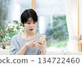 Young woman sitting on sofa and using smartphone 134722460