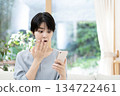 Young woman sitting on sofa and using smartphone 134722461