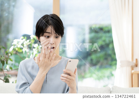 Young woman sitting on sofa and using smartphone 134722461