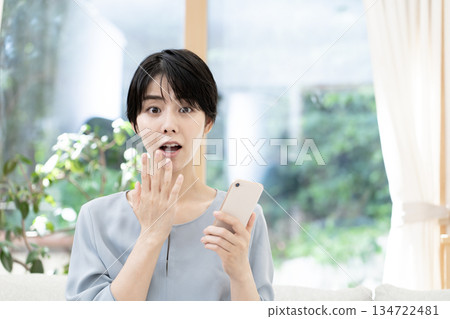 Young woman sitting on sofa and using smartphone 134722481