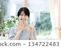 Young woman sitting on sofa and using smartphone 134722483