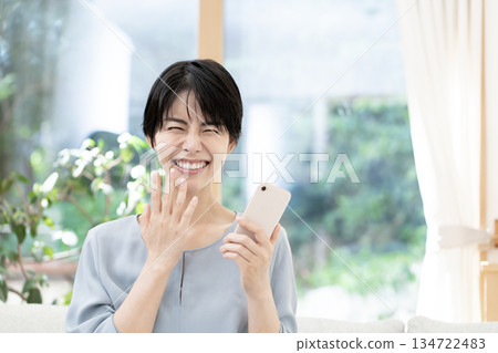 Young woman sitting on sofa and using smartphone 134722483